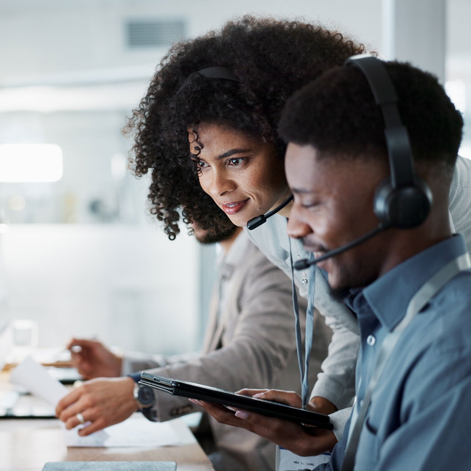 Coworkers wearing headsets reviewing information on screen